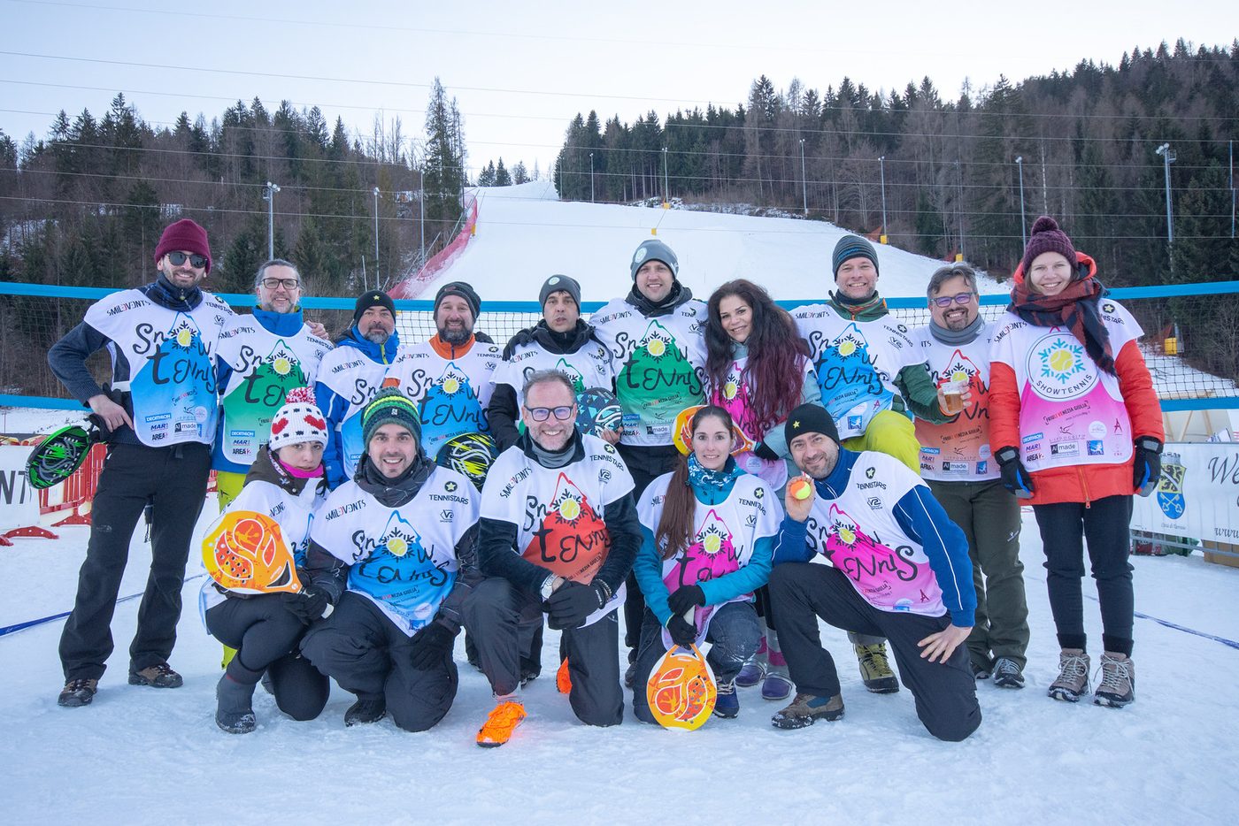 Il gruppo dei partecipanti allo Snow Tennis in posa sulla neve, con la pista da sci alle spalle